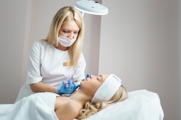 Il cosmetologo medico femminile fa iniezioni di acido ialuronico per l'aumento delle labbra del paziente