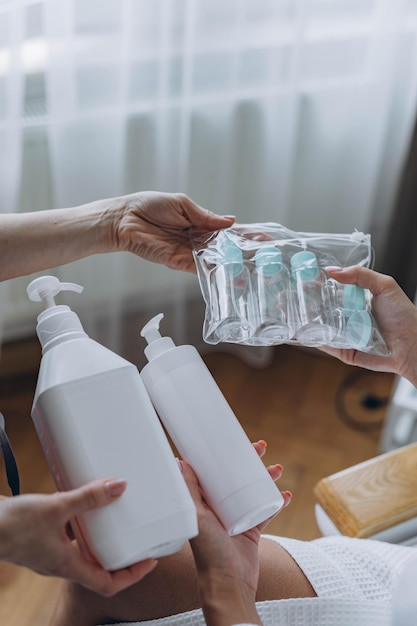 Il cosmetologo mostra al cliente un prodotto cosmetico e un modello di bottiglia di plastica da viaggio.