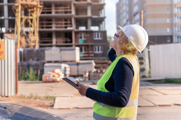 Il costruttore della donna con un tablet registra gli indicatori. Donna di mezza età che lavora in un cantiere edile.