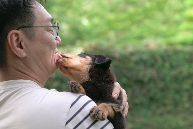 Il cucciolo di cane lecca il maschio adulto sul suo viso