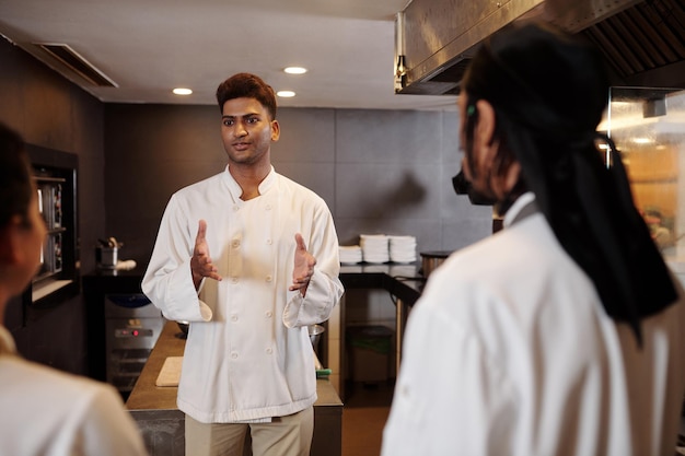 Il cuoco di un ristorante indiano che parla alla sua squadra per rallegrarli prima del lungo turno