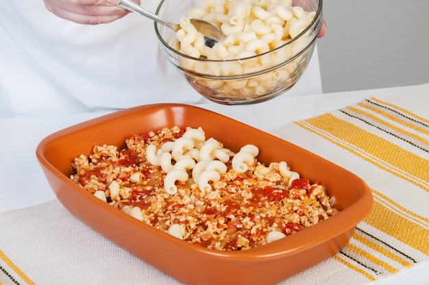 Il cuoco prepara una casseruola di carne con la pasta.