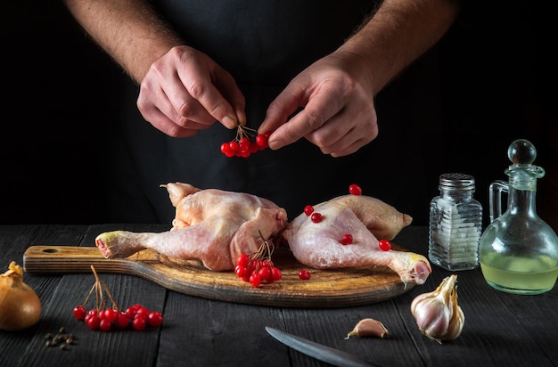 Il cuoco professionista prepara le cosce di pollo crude nella cucina del ristorante