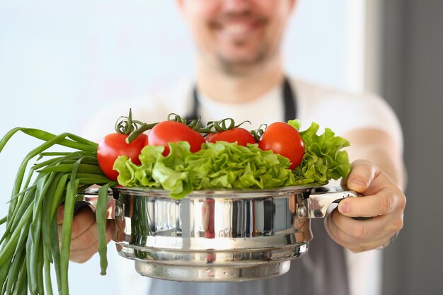 Il cuoco sta tenendo un'insalata di pomodori e cipolle verdi in casseruola