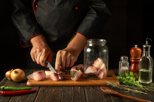 Il cuoco taglia il pesce crudo su una tavola da taglio della cucina Delizioso pranzo di pesce carpa salato per un ristorante o un hotel