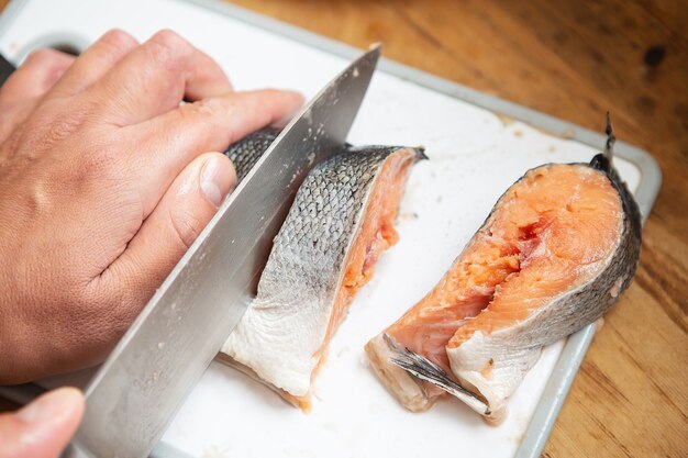 Il cuoco taglia il salmone fresco con un coltello da bistecca affilato. Stile alimentare per una buona salute.