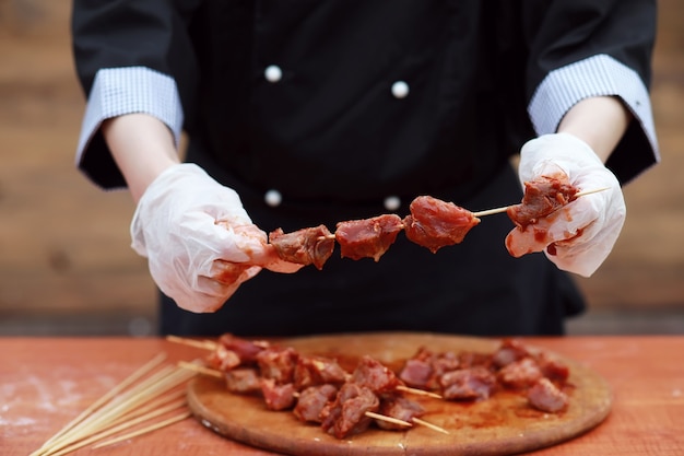 Il cuoco taglia la carne per la cottura del barbecue sul tavolo