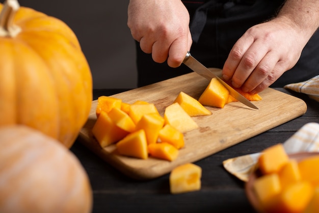 Il cuoco taglia la zucca a pezzi per la cottura.