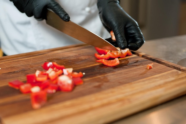 Il cuoco taglia le verdure con un coltello per preparare il piatto Tagliare le verdure