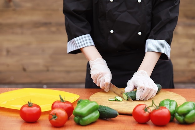 Il cuoco taglia le verdure fresche dell'azienda agricola per la cena sul tavolo