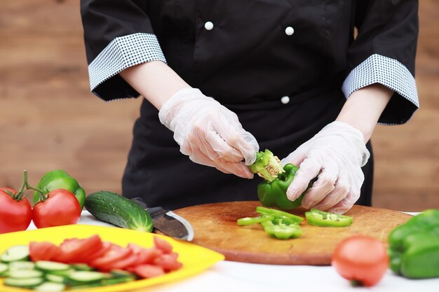 Il cuoco taglia le verdure fresche dell'azienda agricola per la cena sul tavolo