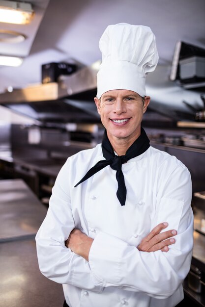 Il cuoco unico maschio felice che sta con le armi ha attraversato in cucina