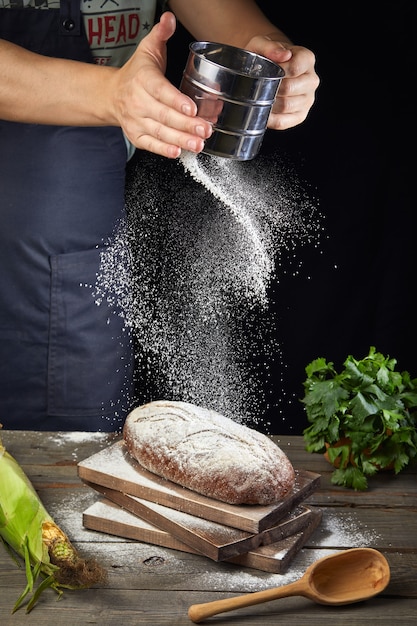 Il cuoco versa la farina sul pane