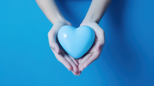 Il cuore carino con la consistenza blu nelle mani su uno sfondo blu pulito La gentilezza è nelle mani dell'uomo