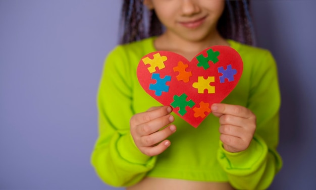 Il cuore con pezzi di puzzle multicolori in primo piano tiene un bambino Problemi sociali nella società