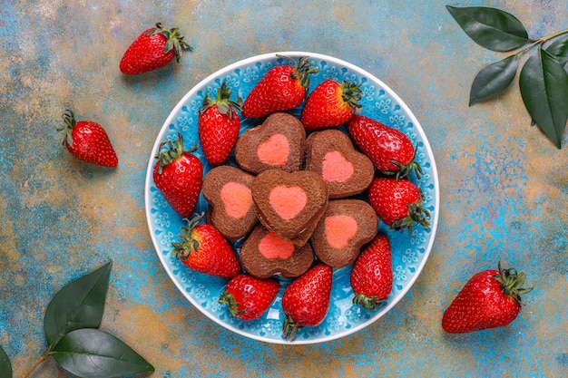 Il cuore ha modellato i biscotti con le fragole fresche, vista superiore della fragola e del cioccolato