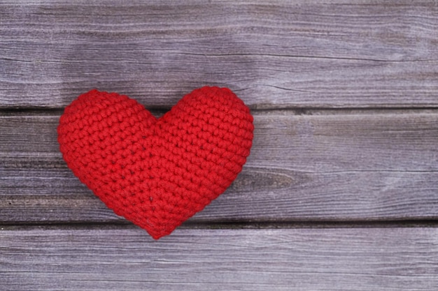 Il cuore rosso si trova su un fondo strutturato di legno grigio. Concetto di amore. Foto di alta qualità