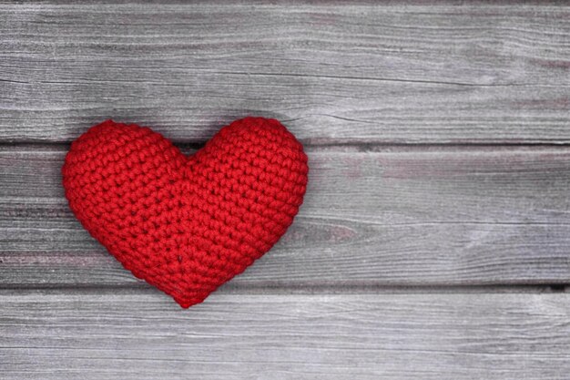 Il cuore si trova su un fondo strutturato di legno grigio. Concetto di amore. Foto di alta qualità