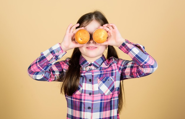 Il cupcake un dolcetto in miniatura Bambina divertente che copre gli occhi con le torte Bambino piccolo che si diverte con i cupcake Bambino giocoso che cucina i cupcakes a casa Godersi il gusto preferito dei cupcake