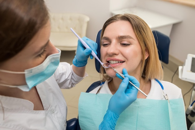 Il dentista controlla i denti di un giovane paziente seduto su una poltrona del dentistaDentista e paziente nello studio dentistico Il concetto di trattamento dentale