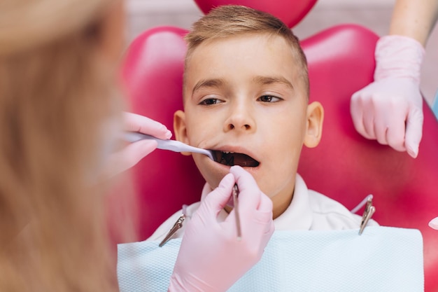 Il dentista della donna fa un esame dentale della bocca del ragazzo