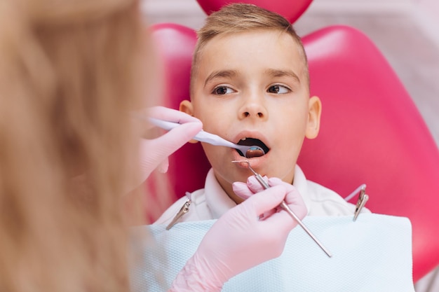 Il dentista della donna fa un esame dentale della bocca del ragazzo
