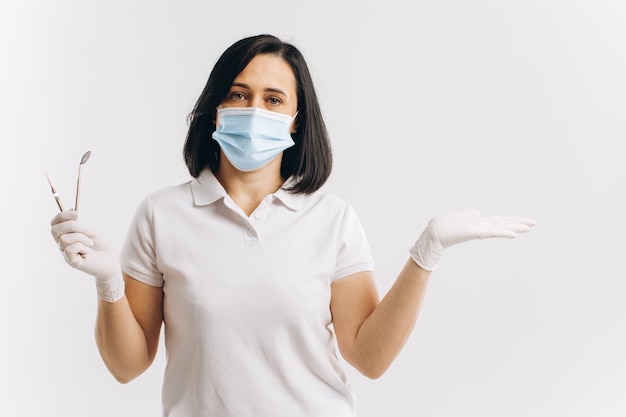 Il dentista della donna in una maschera medica mostra qualcosa su uno spazio della copia