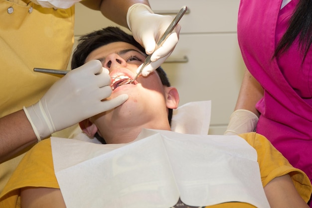 Il dentista della donna tratta i denti del ragazzo con un trapano