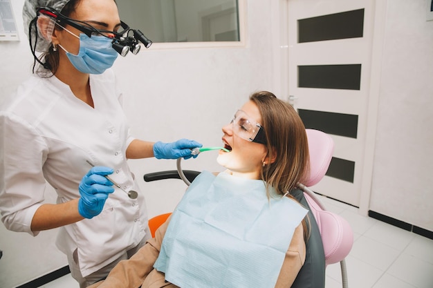 Il dentista della donna tratta i denti di una giovane donna che si trova nella clinica. il medico cura i denti.
