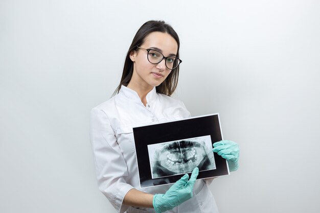 Il dentista della ragazza in camice bianco tiene un'istantanea dei denti del paziente.