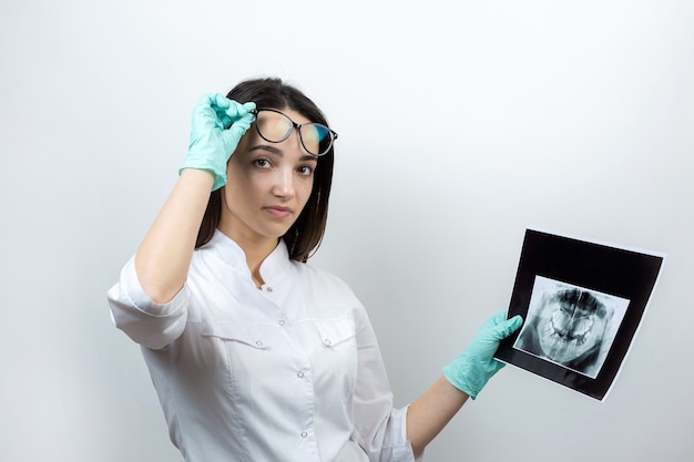 Il dentista della ragazza in camice bianco tiene un'istantanea dei denti del paziente.