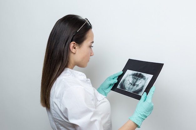 Il dentista della ragazza in camice bianco tiene un'istantanea dei denti del paziente.