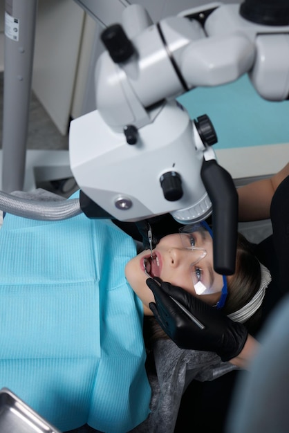 Il dentista esamina i denti del bambino con un microscopio. Attrezzatura odontoiatrica professionale.