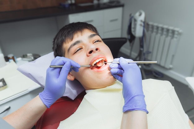 Il dentista esamina i denti di un ragazzo di 13 anni nella clinica odontoiatria pediatrica