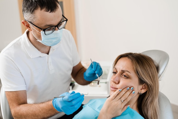 Il dentista esamina la donna con mal di denti alla consultazione e al trattamento dal dentista in odontoiatria Il dentista tratta i denti della carie per la ragazza