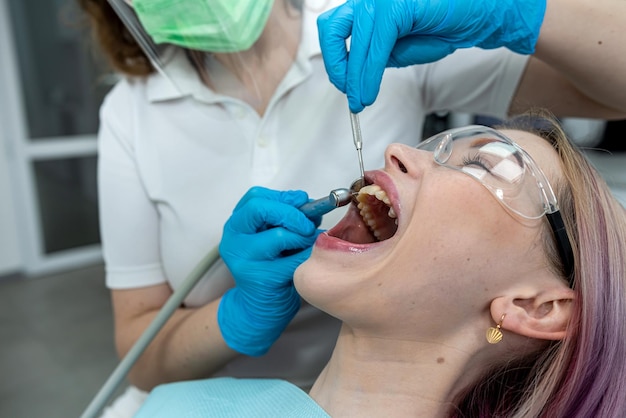 Il dentista esamina tratta i denti cariati con l'aiuto di speciali attrezzature mediche per strumenti dentali