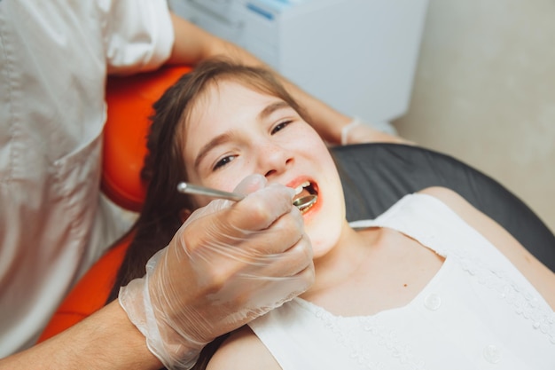 Il dentista esegue una procedura di esame su una bambina carina Bambina seduta nell'ufficio del dentista