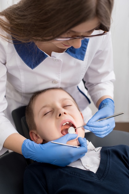 Il dentista femminile esamina i denti del bambino paziente