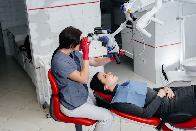 Il dentista guarda attraverso un microscopio ed esegue un intervento chirurgico sul paziente