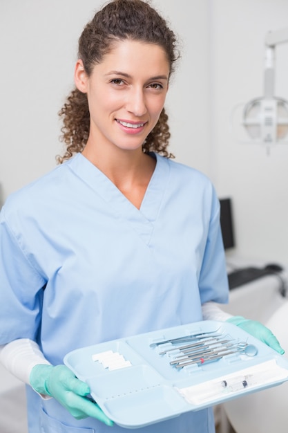 Il dentista in blu frega tenendo il vassoio di strumenti