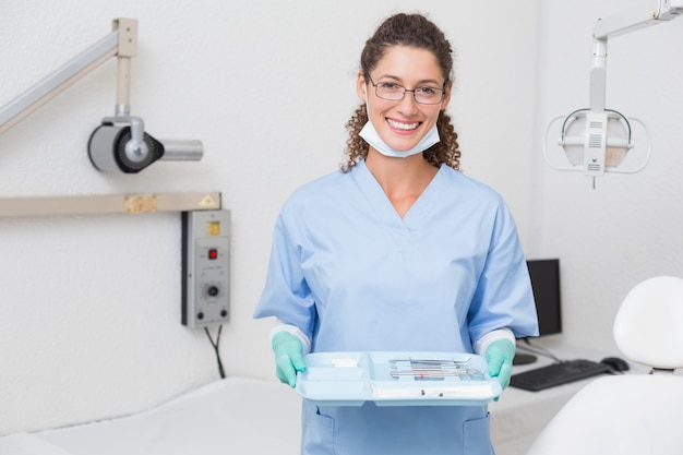 Il dentista in blu frega tenendo il vassoio di strumenti