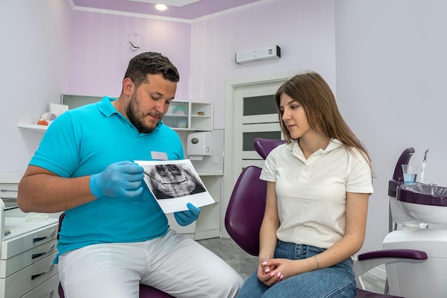 Il dentista maschio spiega il piano per un ulteriore trattamento dentale alla paziente femminile nella clinica