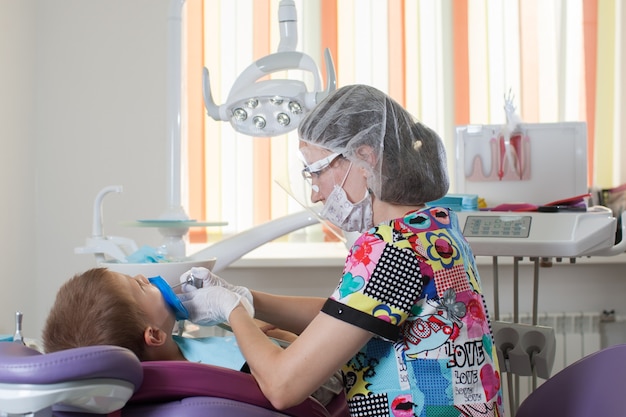 Il dentista medico dei bambini piccoli tratta i denti con dispositivi diversi