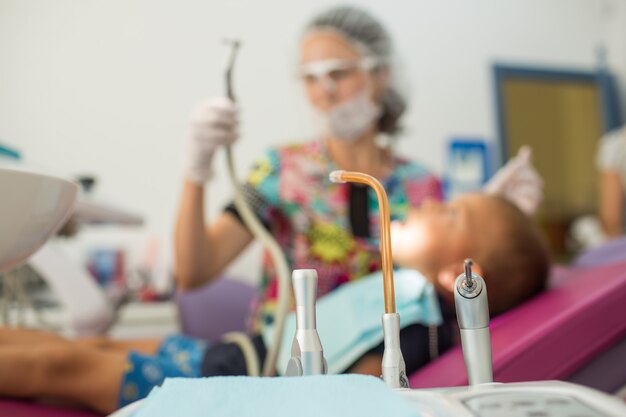 Il dentista medico dei bambini piccoli tratta i denti con dispositivi diversi