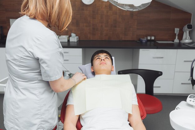 Il dentista mette un tovagliolo dentale sul paziente Preparazione del paziente per un esame dentale