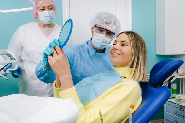 Il dentista mostra al cliente i risultati del suo lavoro allo specchio. Il cliente sorride