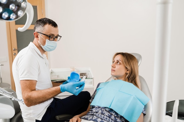 Il dentista mostra la protezione della bocca per lo sbiancamento dei denti in odontoiatria Il medico ortodontista consulta la paziente sulla procedura di sbiancamento dei denti a casa