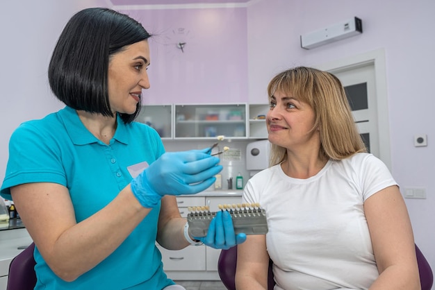 Il dentista seleziona il tono dei denti bianchi del paziente con un pallet