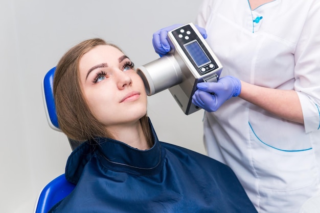 Il dentista si prepara a realizzare un'immagine a raggi x del dente per una ragazza in clinica dentale