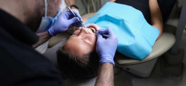 Il dentista tratta i denti con carie a una paziente femminile nella clinica dentale